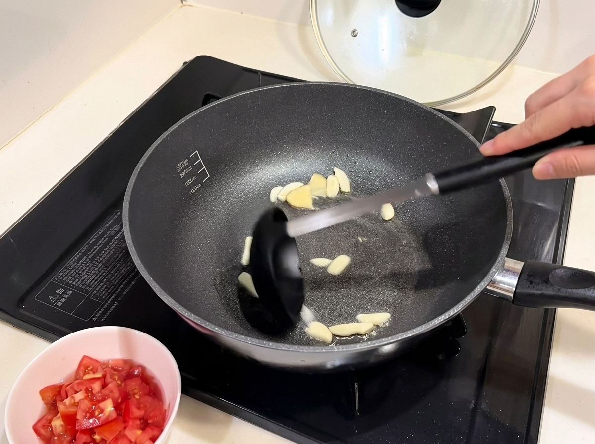 Rote Zwiebelstücke werden in einer Pfanne mit angebratenem Knoblauch weich gedünstet.
