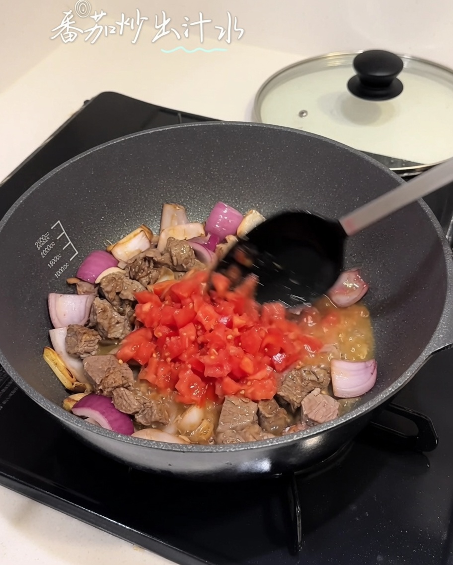 Gewürfelte Tomaten werden in eine Pfanne mit Rindfleisch-Zwiebel-Mischung eingerührt.