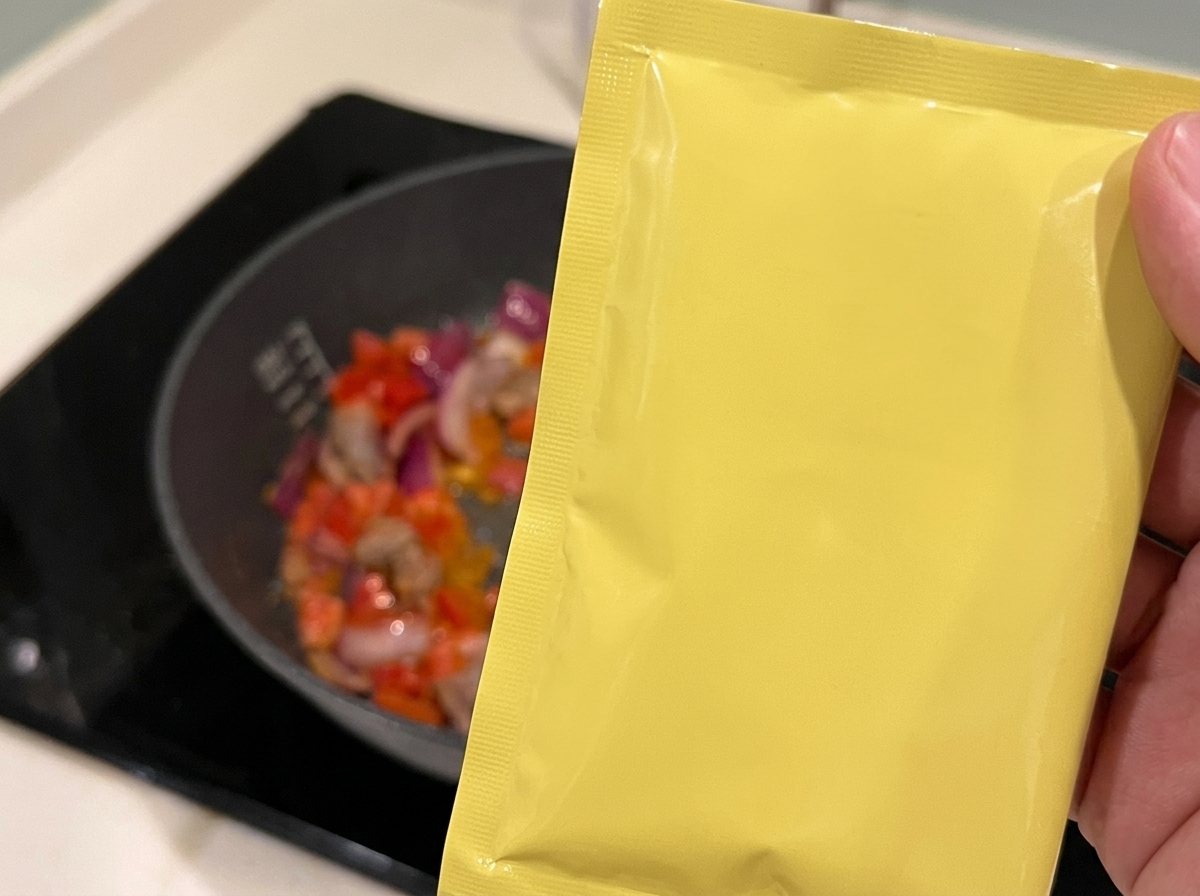 Kochwein wird über die Mischung aus angebratenem Rindfleisch, Tomaten und Zwiebeln in der Pfanne gegossen.