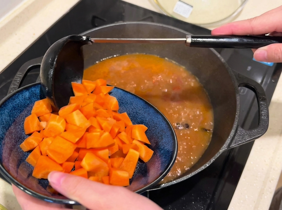 Gewürfelte Karotten werden in eine Pfanne mit kochender Rinderbrühe gegeben.