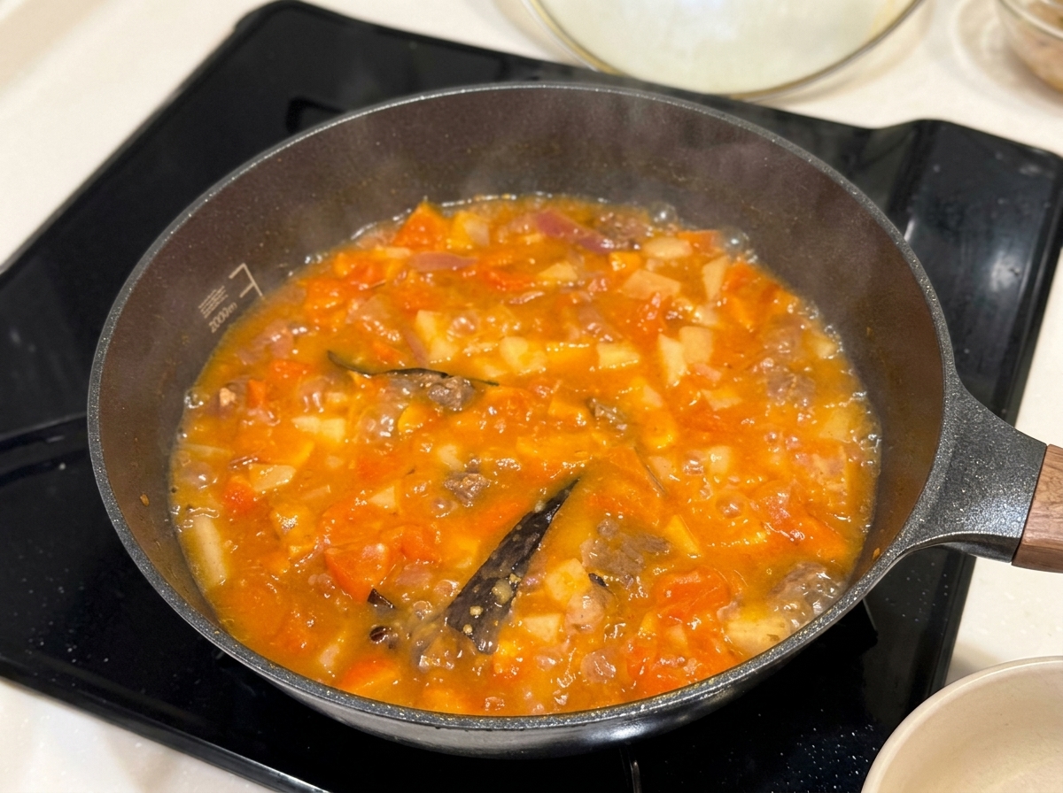 Feste Curry-Gewürzblöcke werden in den köchelnden Eintopf gegeben.