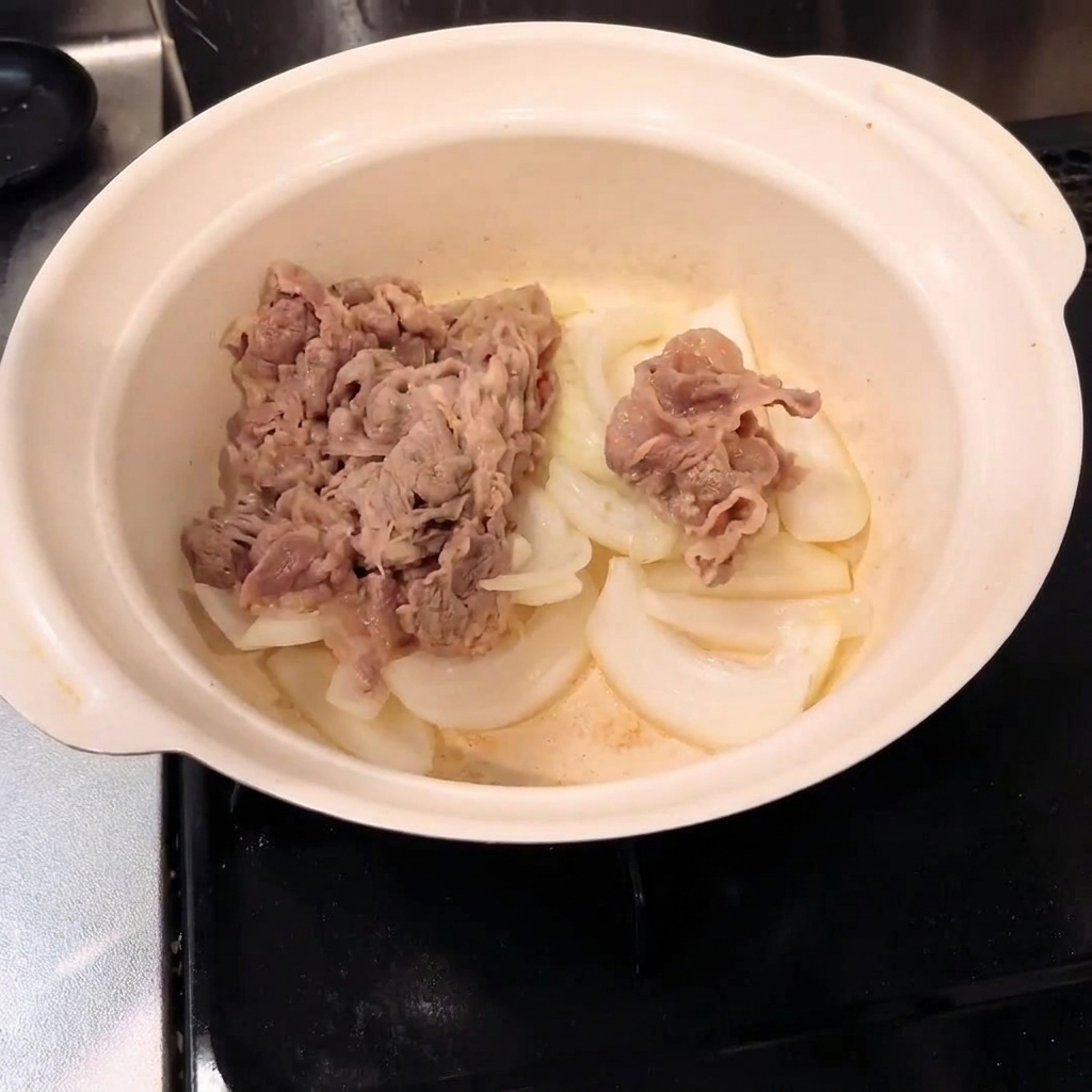 Blanchiertes Rindfleisch vermischt mit Zwiebeln in einem Kochtopf.