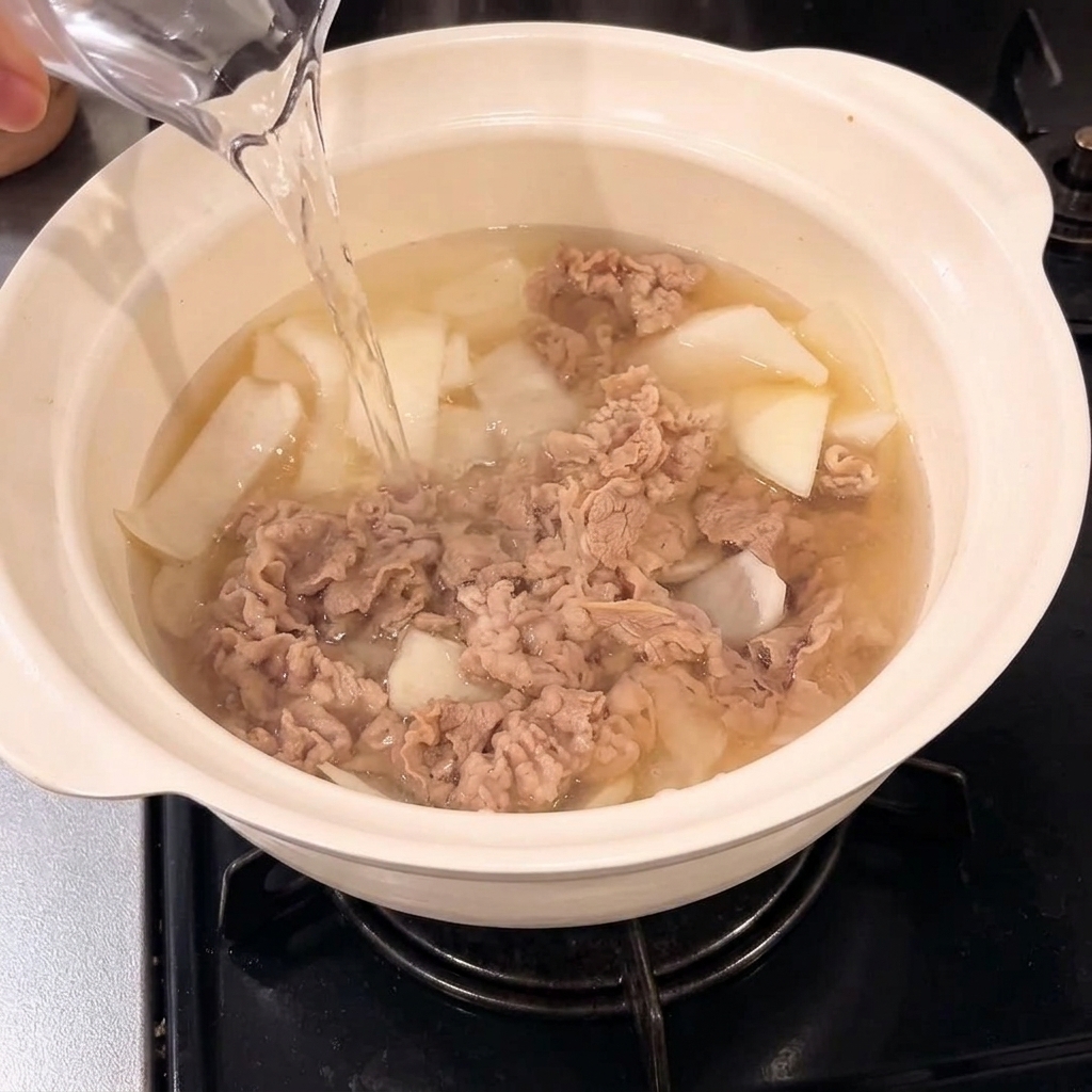 Wasser wird in den Topf zur Rindfleisch-Zwiebel-Mischung gegossen.