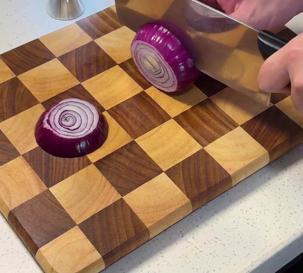 Rote Zwiebel wird auf einem Holzschneidebrett gewürfelt.