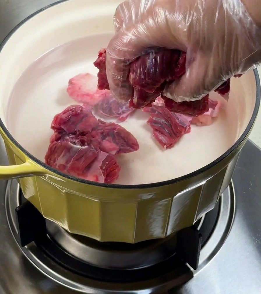 Rinderbrust wird in einem Topf mit Wasser und Aromaten blanchiert.