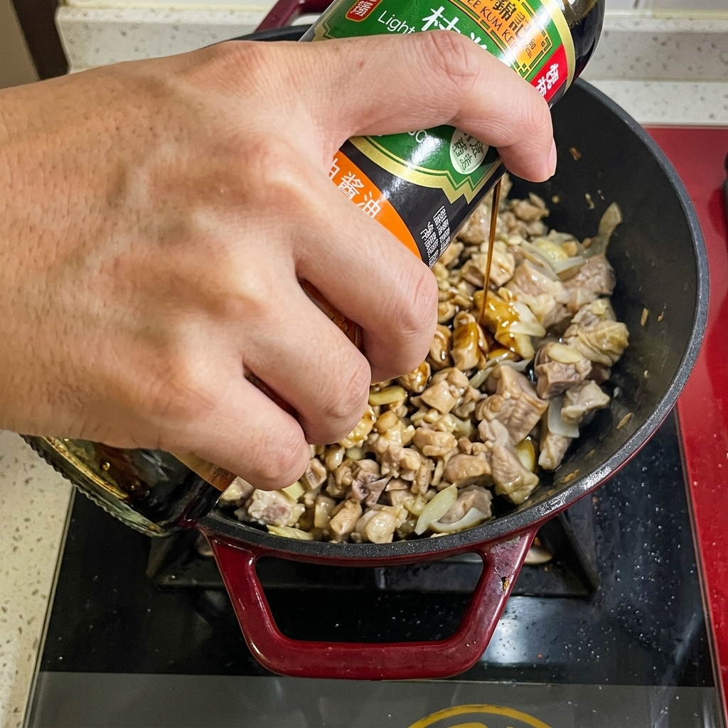 Sojasauce wird aus einer Flasche über das Rindfleisch in die Pfanne gegeben.