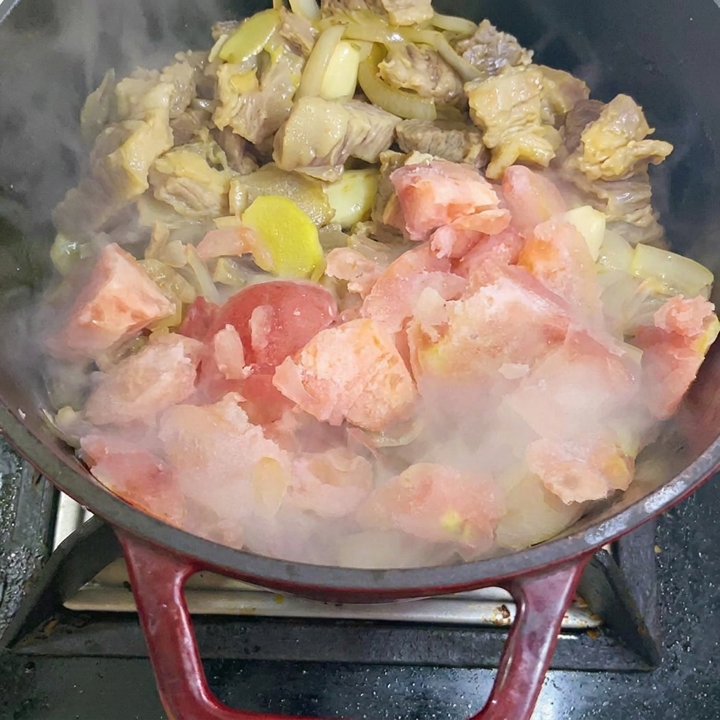 Gefrorene Tomatenstücke werden in die Pfanne zum Anbraten gegeben.