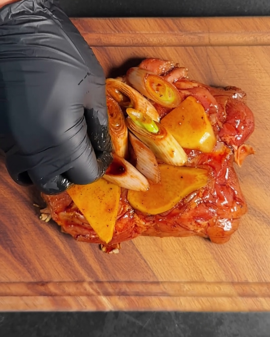 Die Hähnchenstücke in einer Metallschüssel mit Marinade und Aromaten.