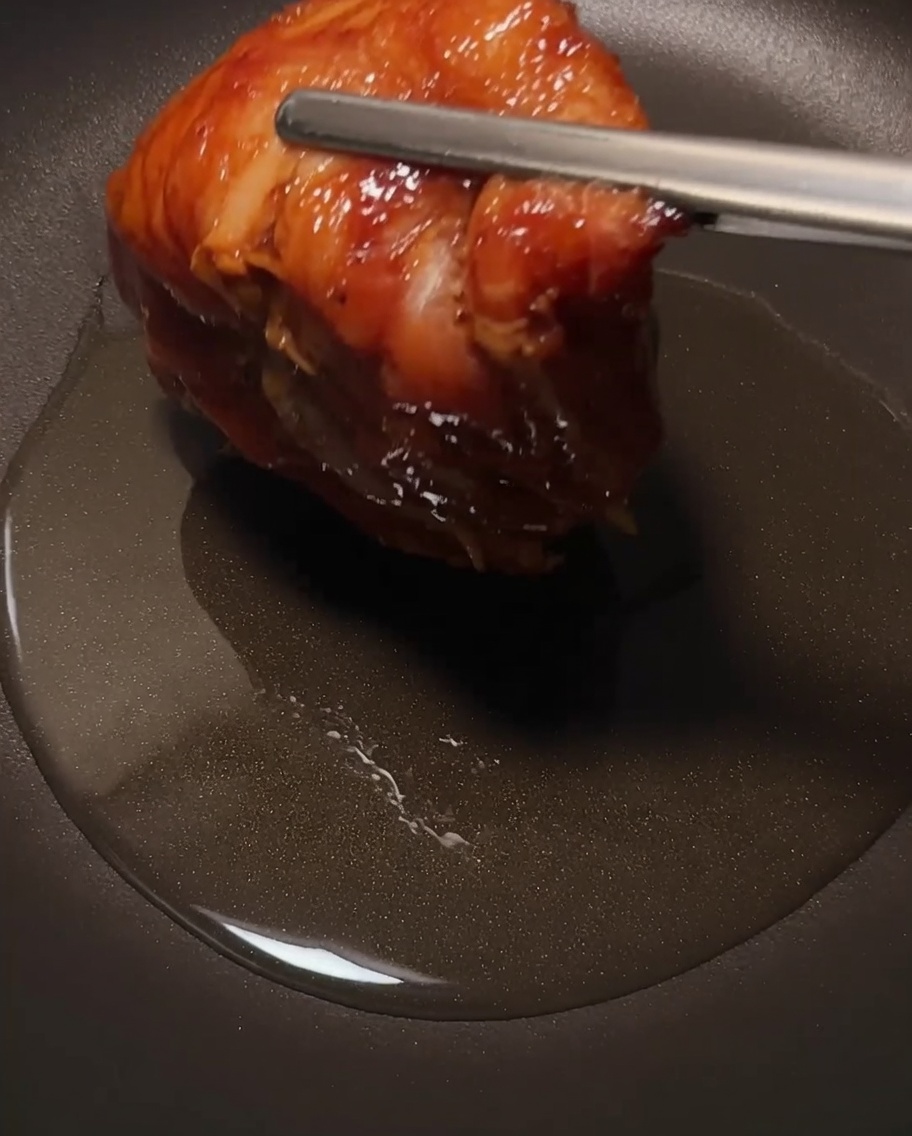 Das Hähnchen brät in einer Pfanne, Fokus auf der knusprigen Haut.