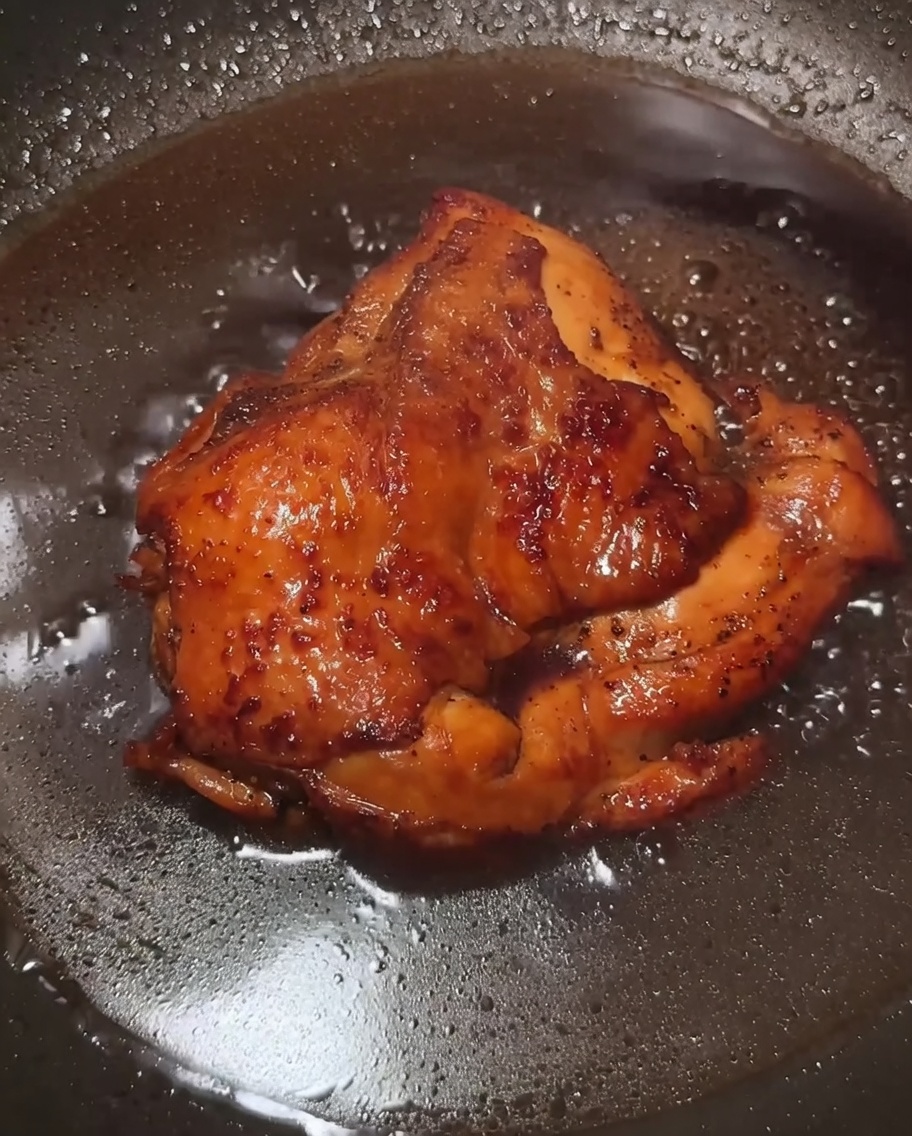 Eine dunkle, glänzende Sauce mit Hähnchen in der Pfanne.