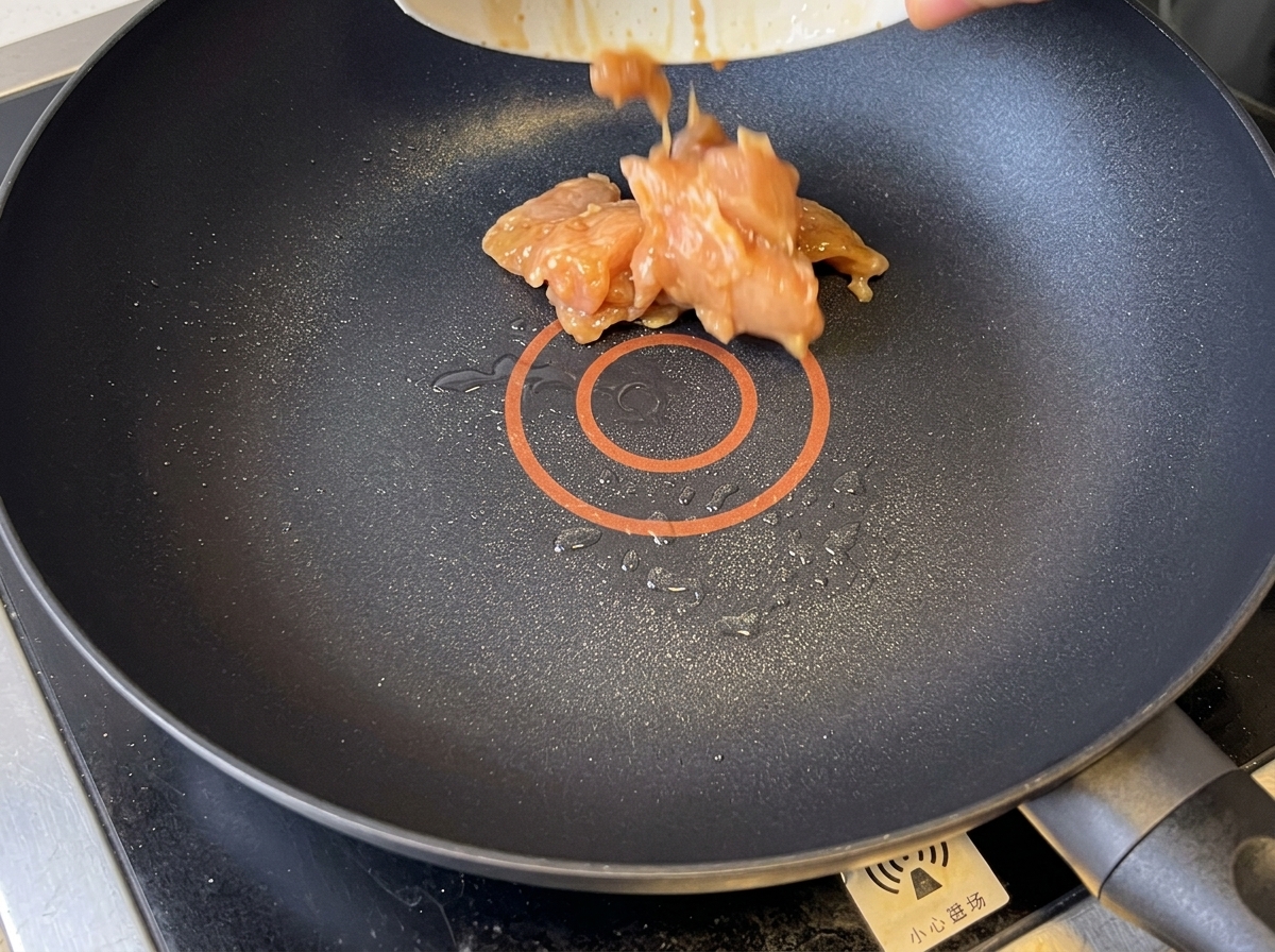 Goldbraune Hähnchenstücke werden in einer beschichteten Pfanne gebraten.
