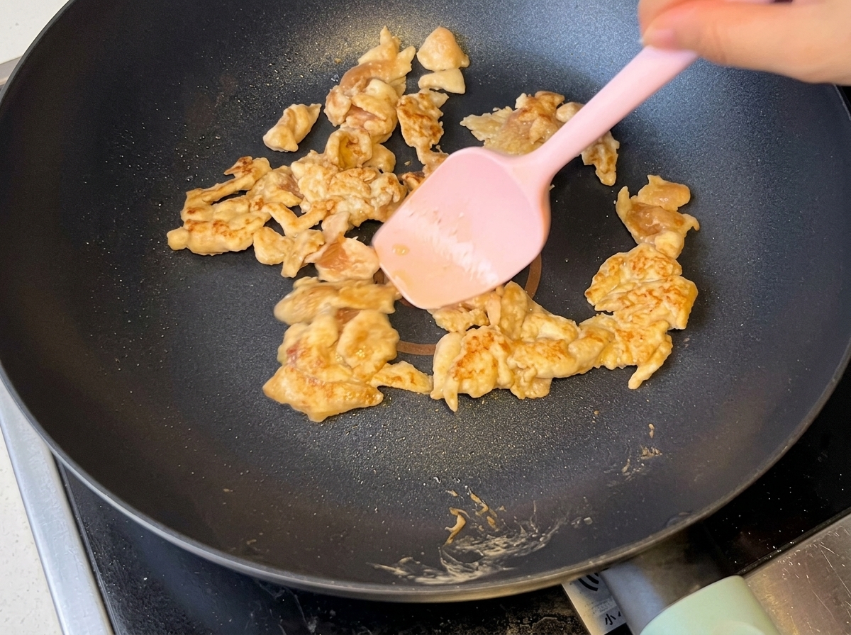 Geschnittene Zwiebeln werden zusammen mit gebräuntem Hähnchen in der Pfanne angebraten.