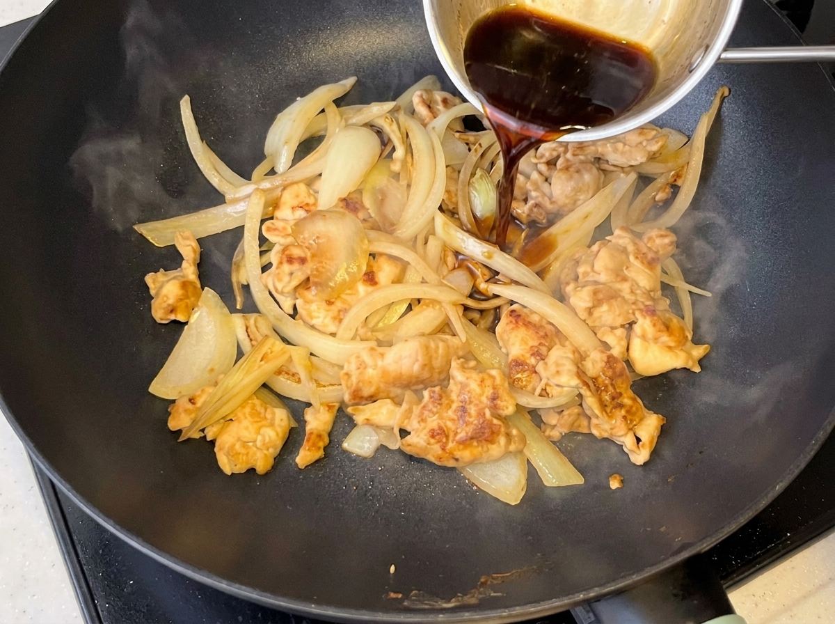 Dunkle Sauce wird in eine Pfanne mit Hähnchen und weichen Zwiebeln gegossen.