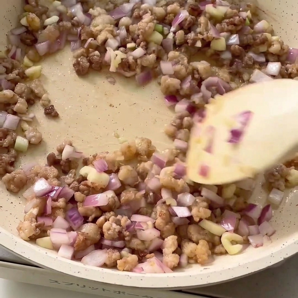 Gewürze werden in die Pfanne mit Hackfleisch und Zwiebeln gegeben.