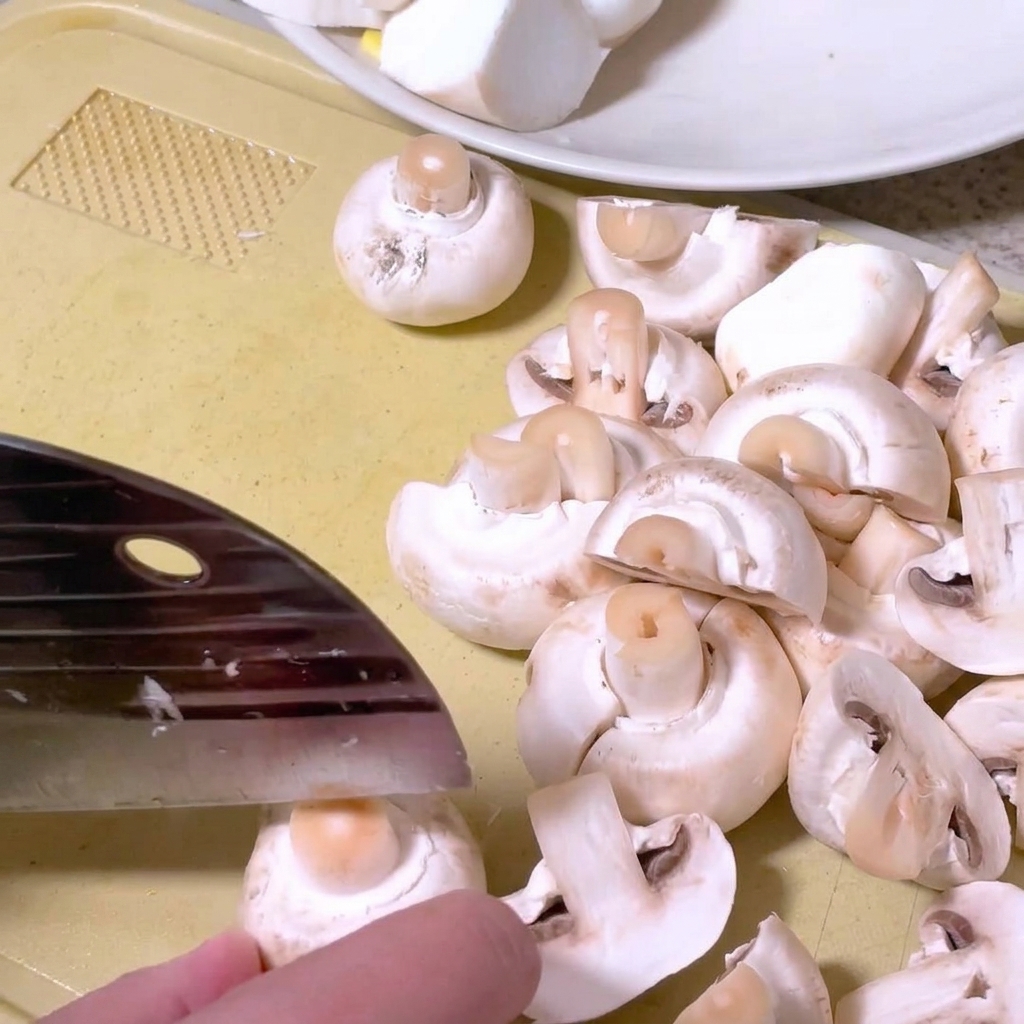 Champignons werden auf einem Schneidebrett mit einem Küchenmesser halbiert.