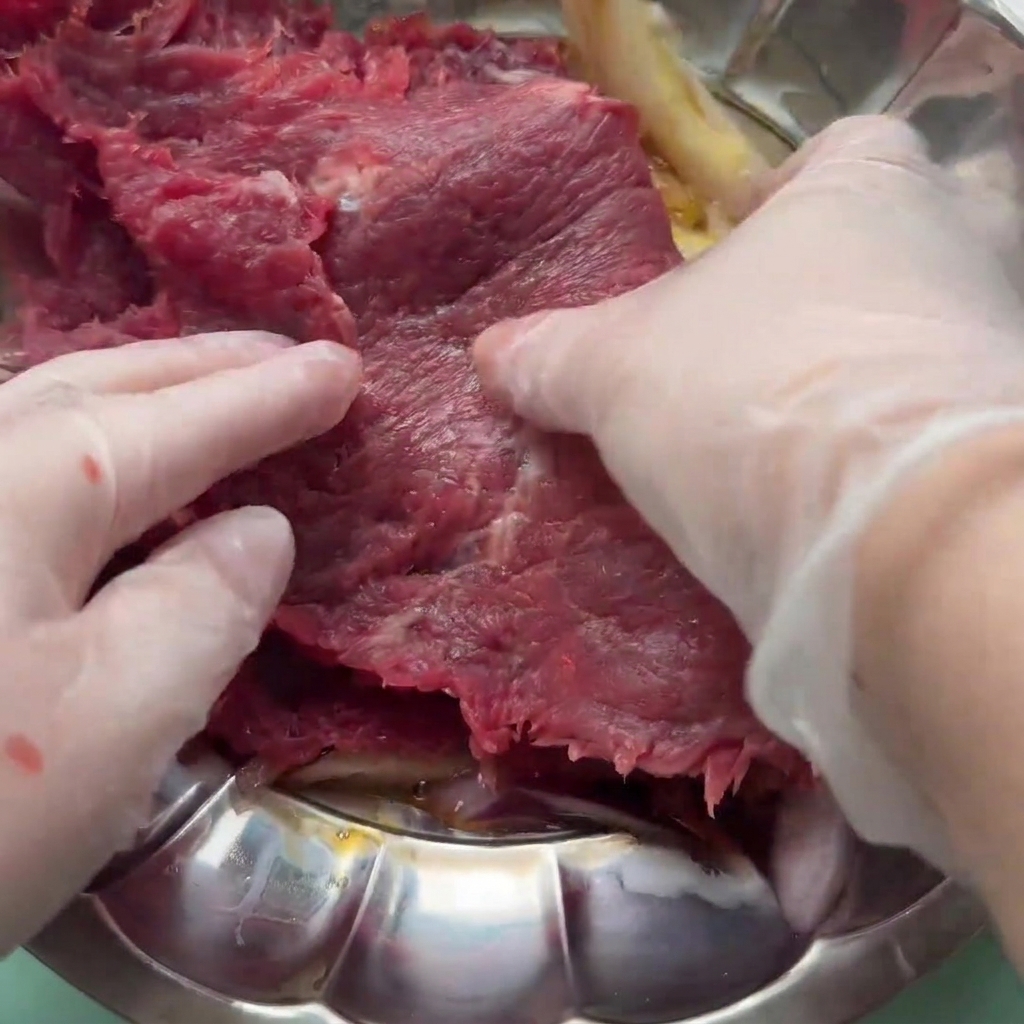 Das Rindfleisch wird in der Marinade aus Ei, Zwiebel und Soßen gewendet.
