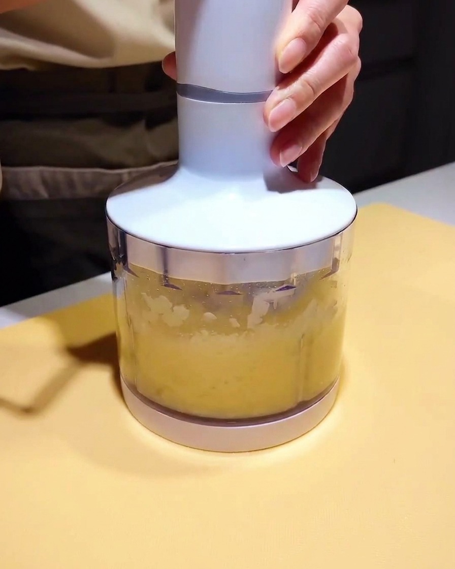 Ein kleiner Mixerbecher gefüllt mit einem hellgelben Püree und dunkler Marinade, bereit zum Mixen.