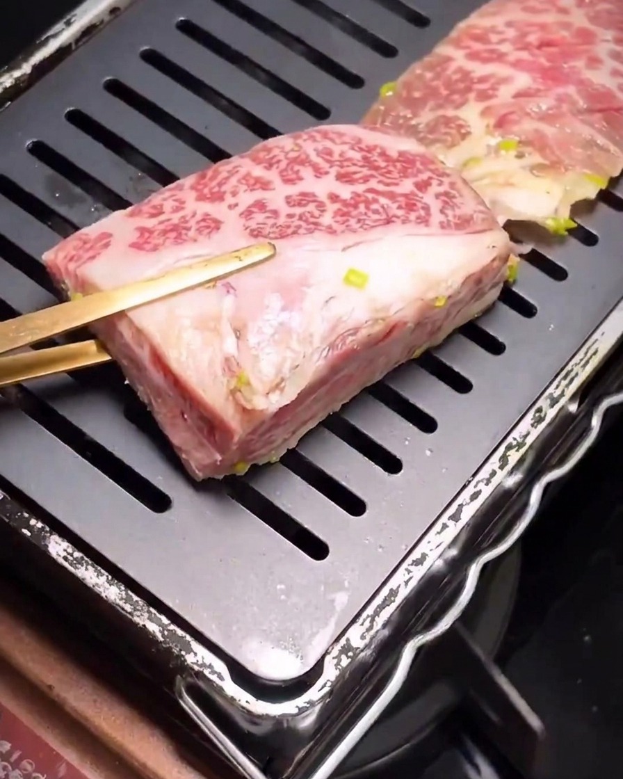 Marinierte Rinderrippchen beginnen auf einer heißen, geriffelten schwarzen Grillpfanne anzubraten.
