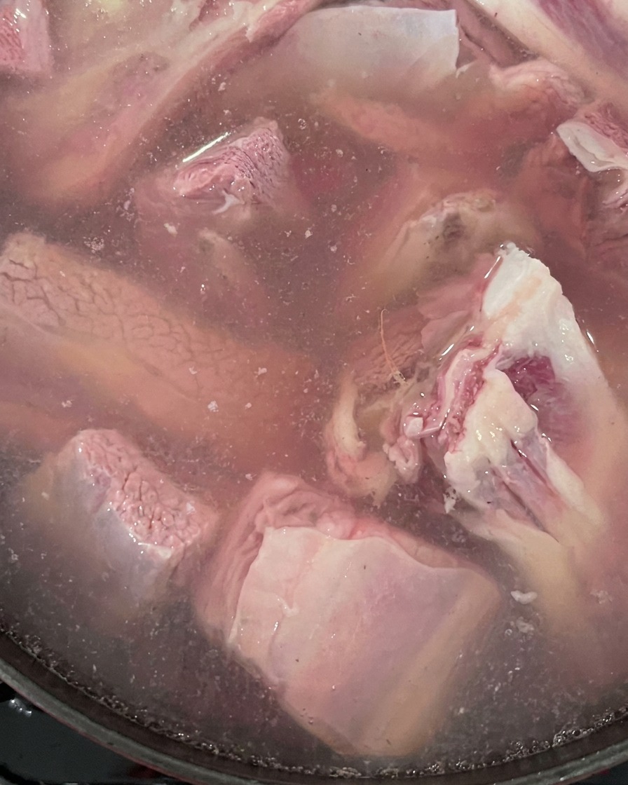 Rohe Rinderrippchen und Ingwer kochen in einem Topf mit Wasser.