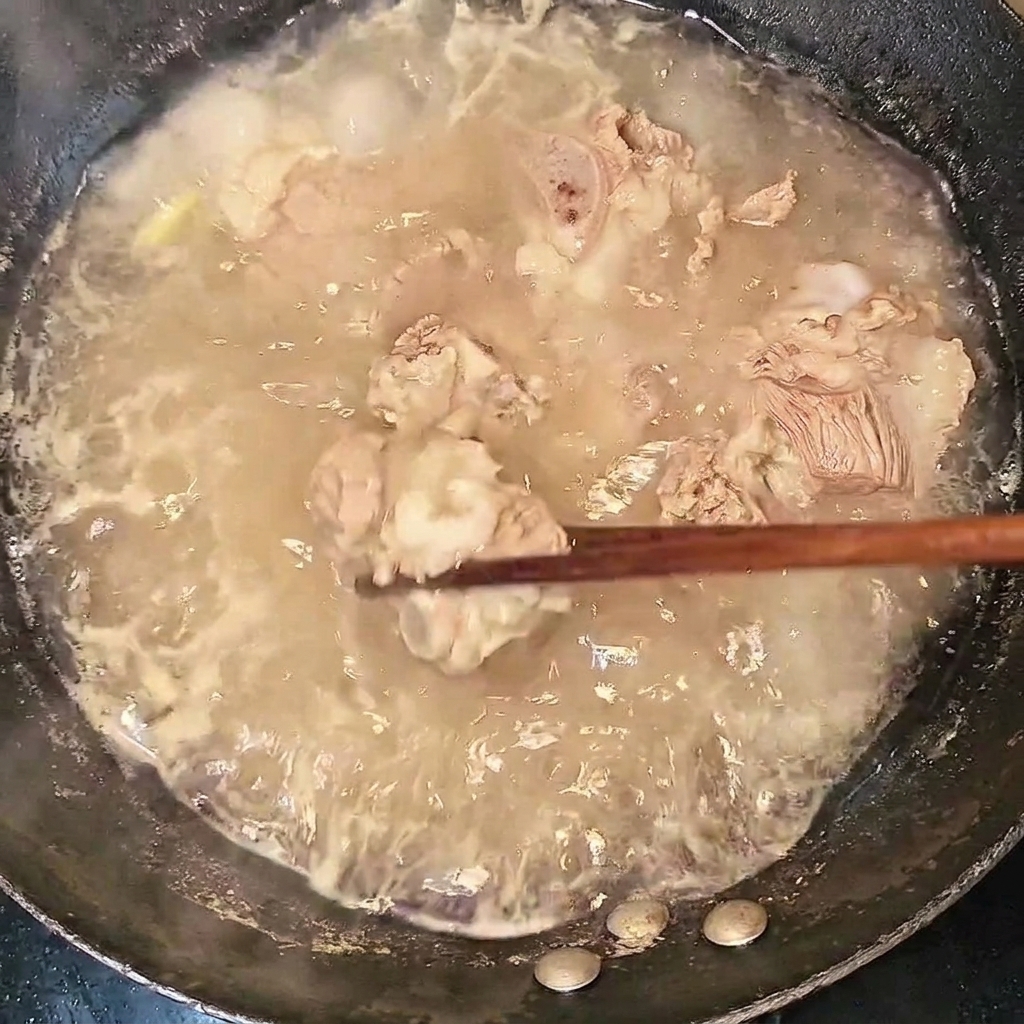Blanchierte Rinderrippchen werden mit Stäbchen aus dem kochenden Wasser gehoben.