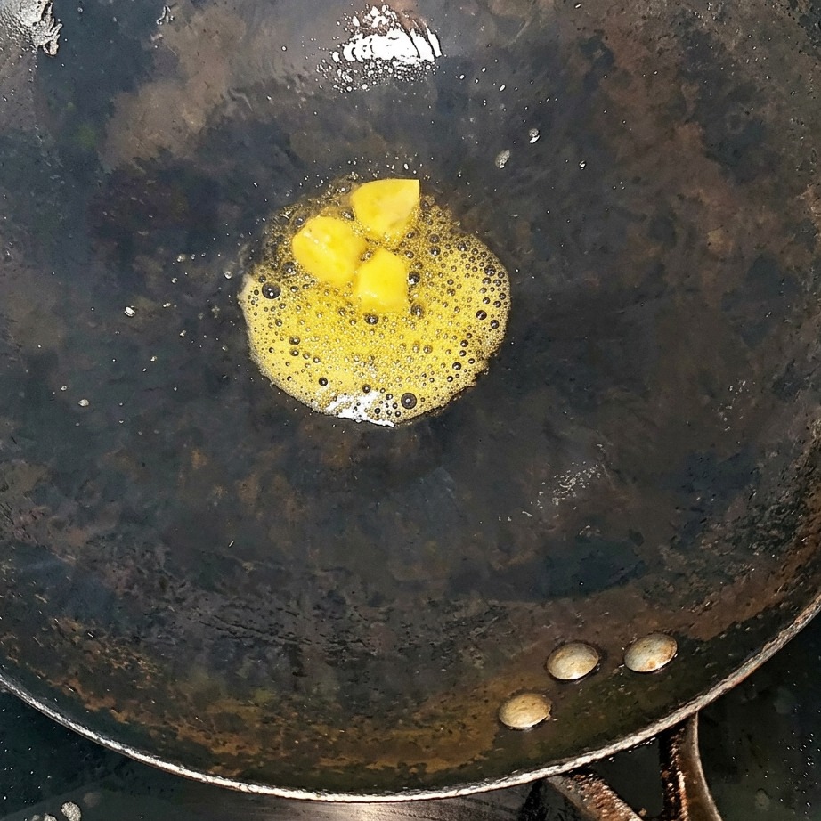 Rinderrippchen und Ingwerscheiben werden in einem heißen Wok angebraten.
