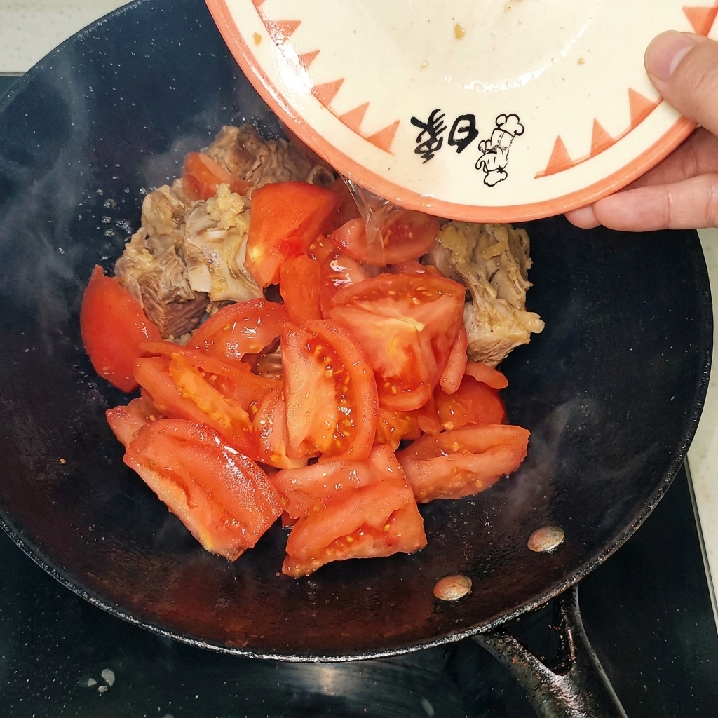 Geschälte Tomatenstücke werden zu den angebratenen Rinderrippchen in den Wok gegeben.