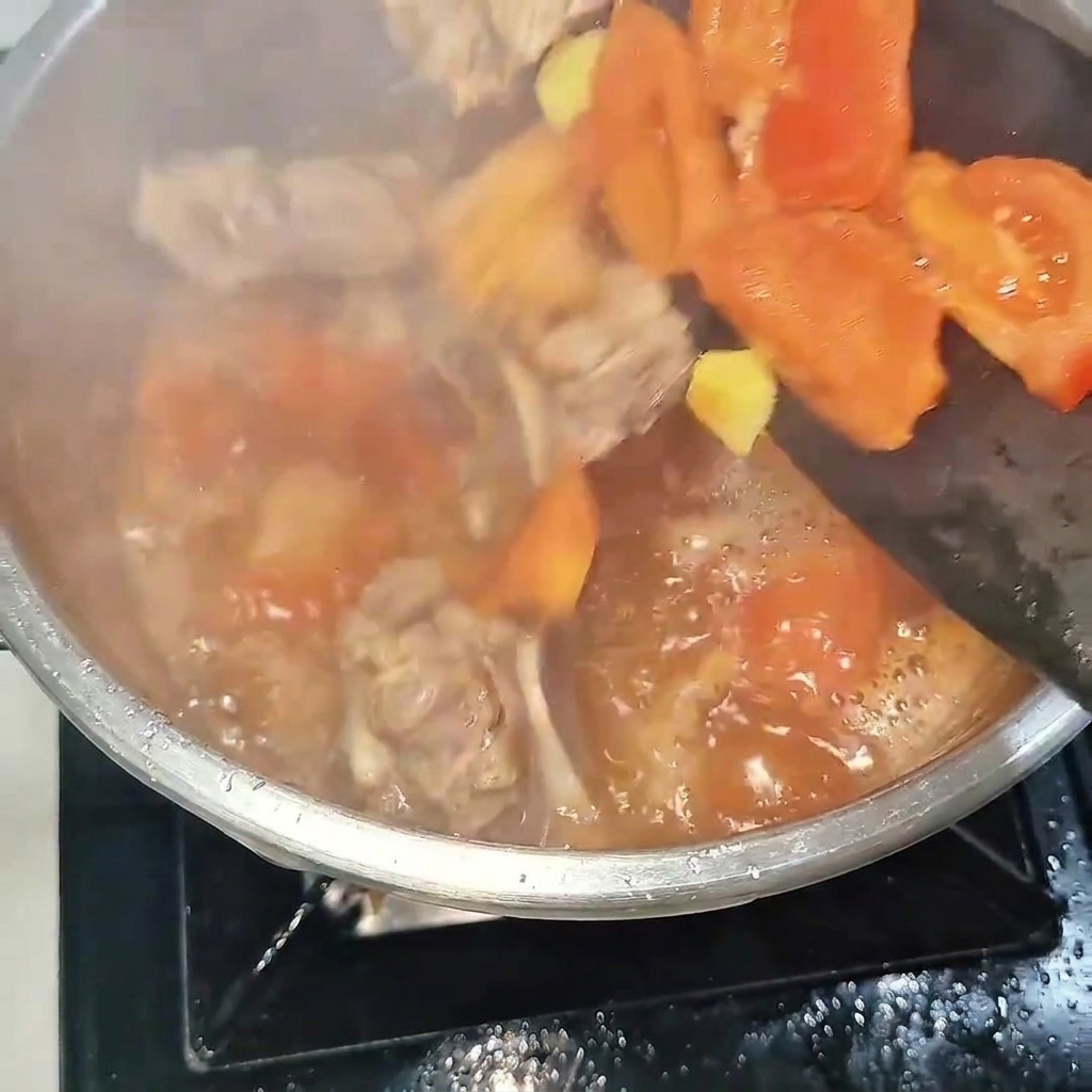 Die Mischung aus Rinderrippchen und Tomaten wird in einen Edelstahl-Schnellkochtopf gefüllt.