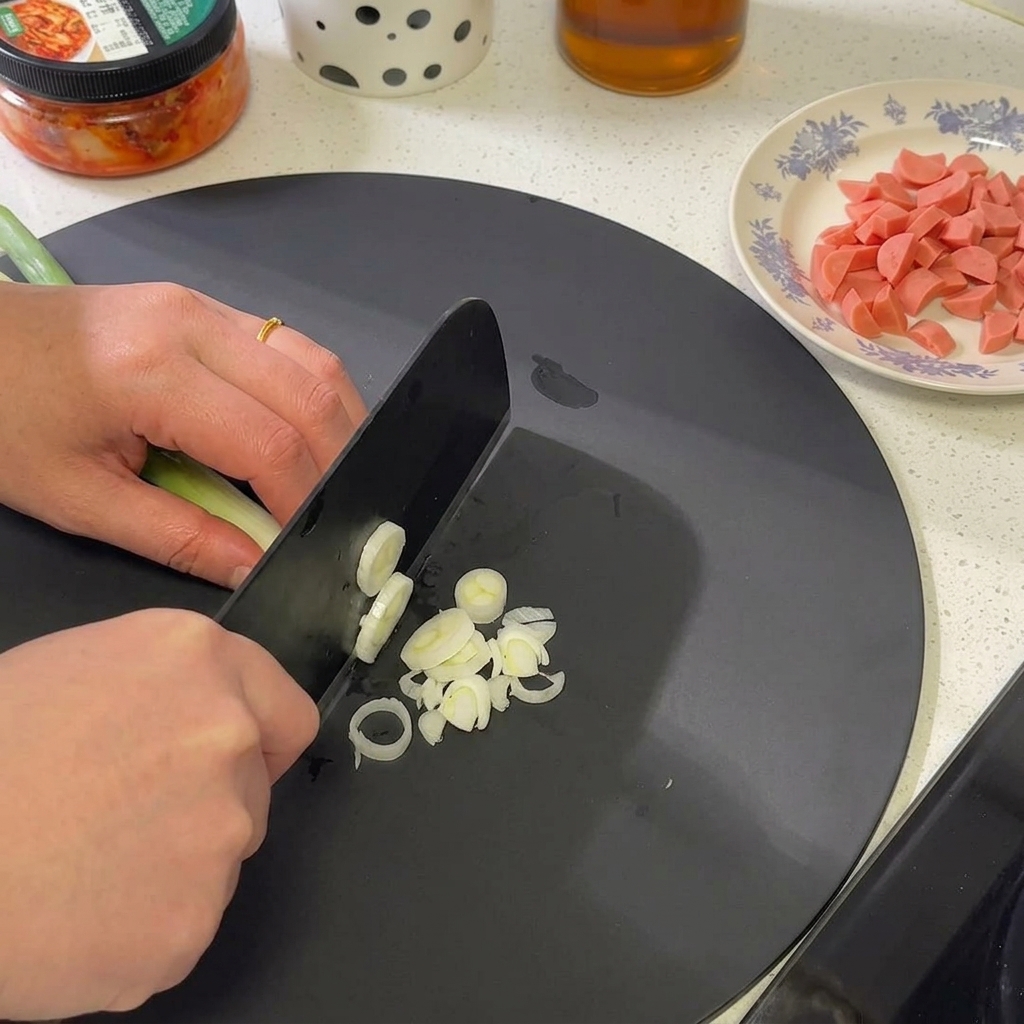 Eine Handvoll Frühlingszwiebeln wird in feine Ringe geschnitten, Fokus auf den weißen und hellgrünen Teilen.