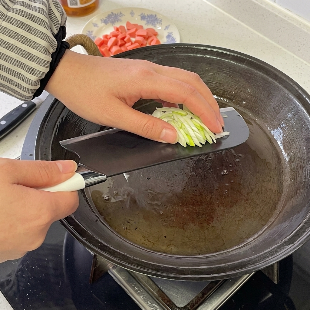 Wurstscheiben und gehackte Frühlingszwiebeln werden in einer heißen Pfanne angebraten.