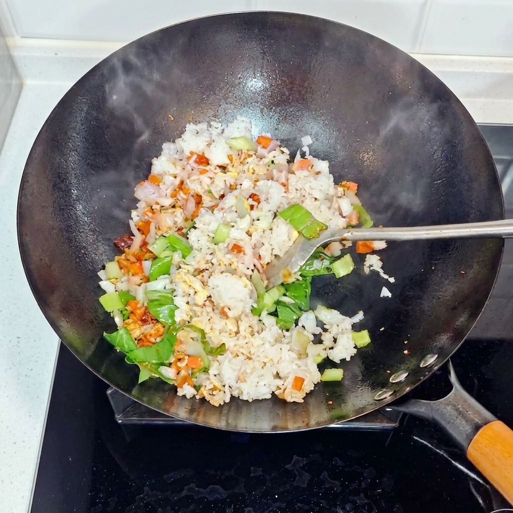 Reis, Zwiebeln und Bok Choy werden im Wok geschwenkt und gebraten.