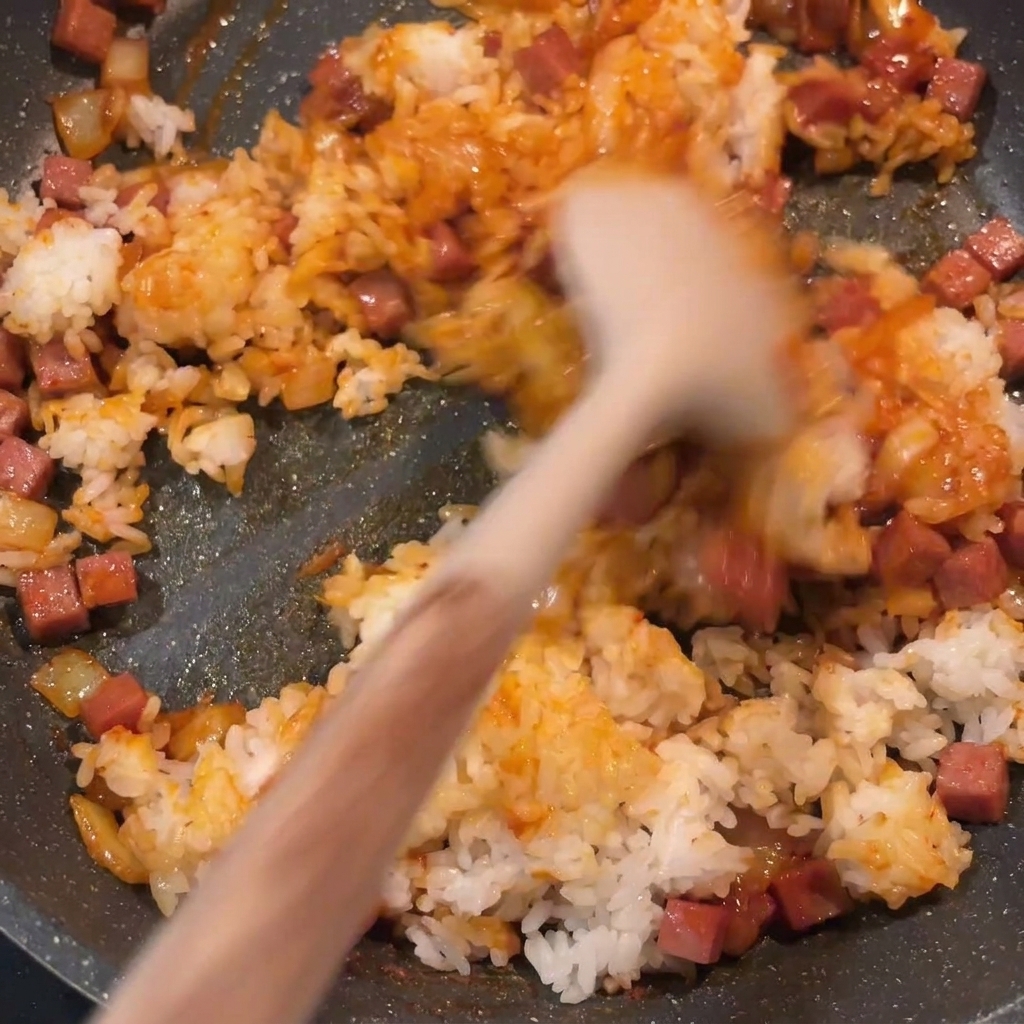 Der fertige Kimchi-gebratene Reis wird in der Pfanne gerührt, gleichmäßig rot und gut vermischt.