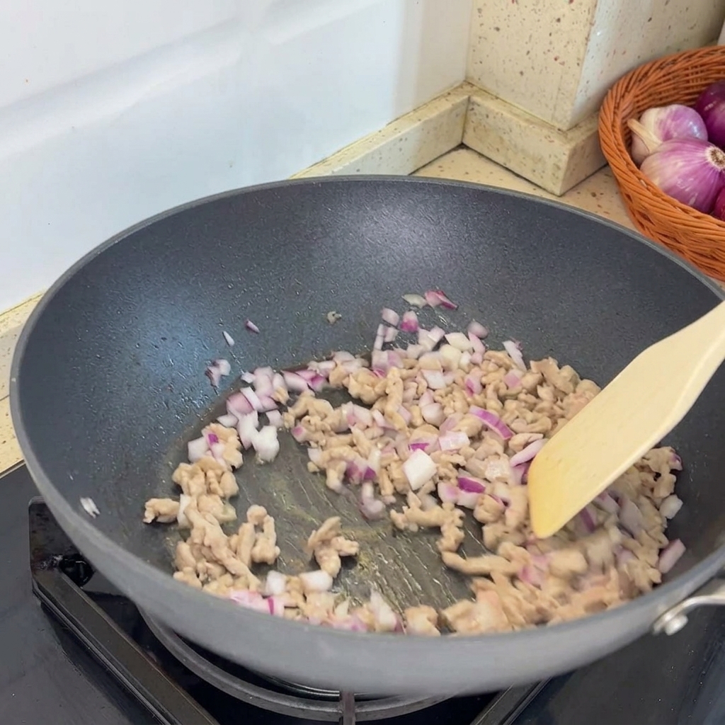 Gehackte Schalotten werden zum angebratenen Hackfleisch in die Pfanne gegeben.