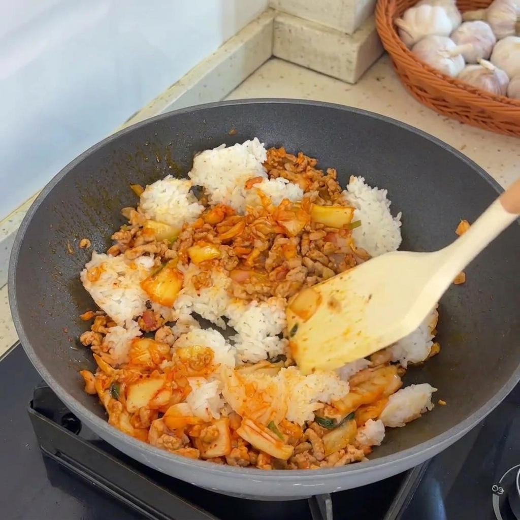 Ein Spatel wendet das Reisgemisch in einem heißen Wok.