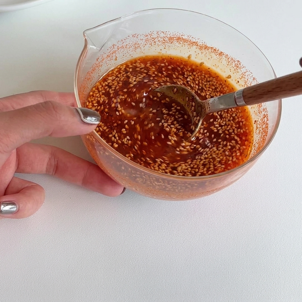 Eine leuchtend rote Sauce wird mit einem Holzlöffel in einer Schüssel glatt gerührt.