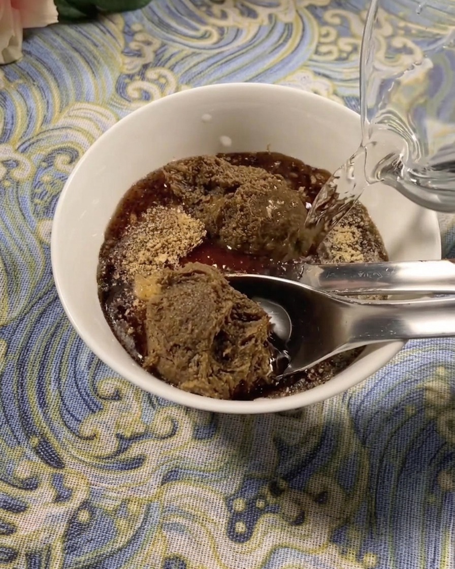 Frische Bohnensprossen am Boden eines dunklen Tontopfs, darauf liegen Fischfilets.