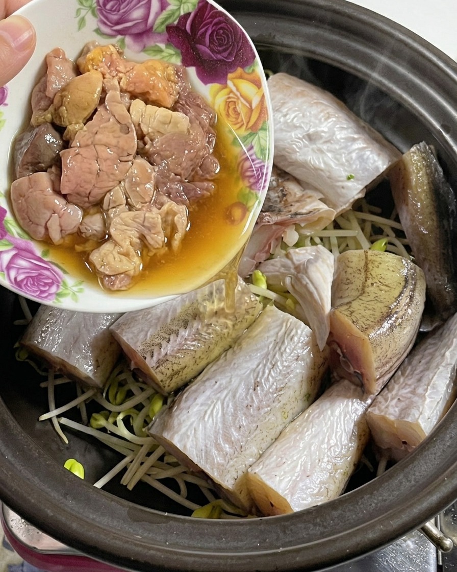 Eine kleine florale Schale gibt frischen, zarten Fischrogen in einen Tontopf mit Fisch und Bohnensprossen.
