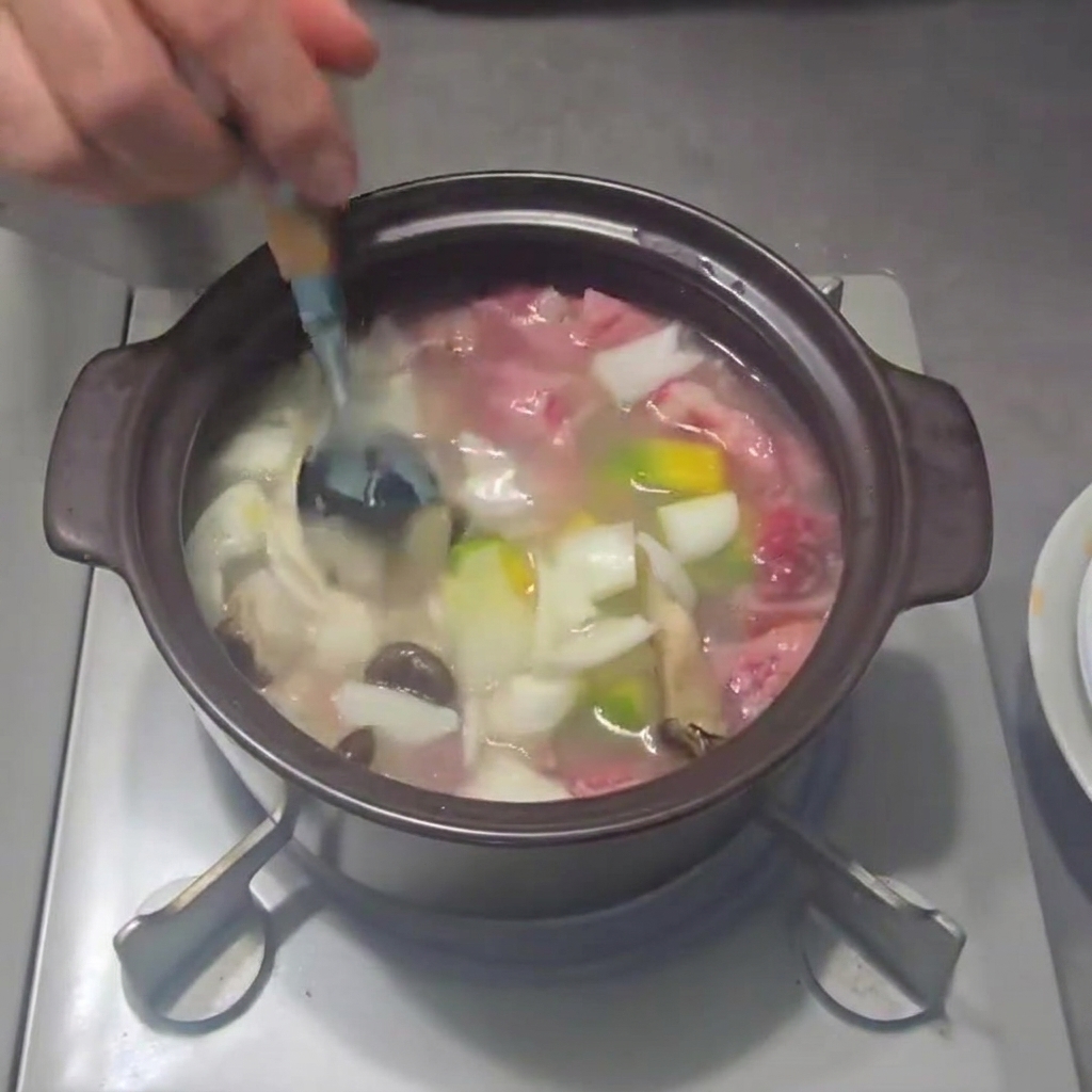 Frühlingszwiebeln werden in den Topf gestreut.