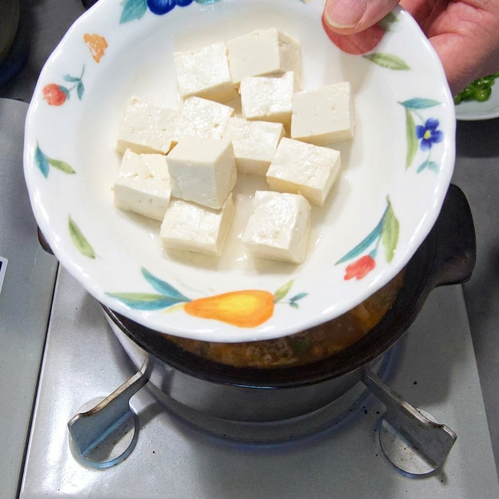 Weiche, weiße Tofuwürfel gleiten in den köchelnden Eintopf.