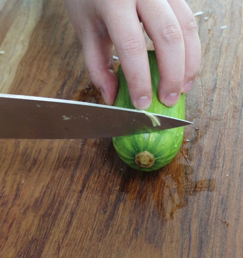 Dreieckig geschnittene Zucchinistücke auf einem Holzbrett.