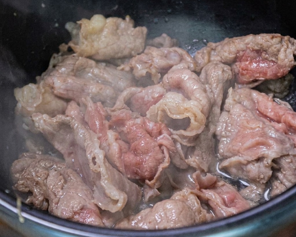 Rindfleisch wird zusammen mit Knoblauch und Frühlingszwiebeln angebraten.