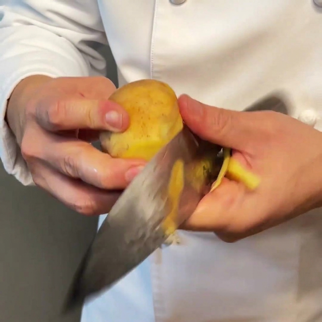 Gleichmäßig gewürfelte Kartoffelstücke auf einem Holzbrett.
