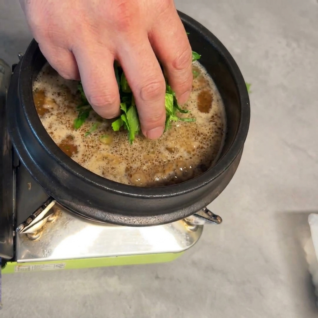 Frische Baby-Bok-Choy-Blätter werden in den köchelnden Eintopf gegeben.