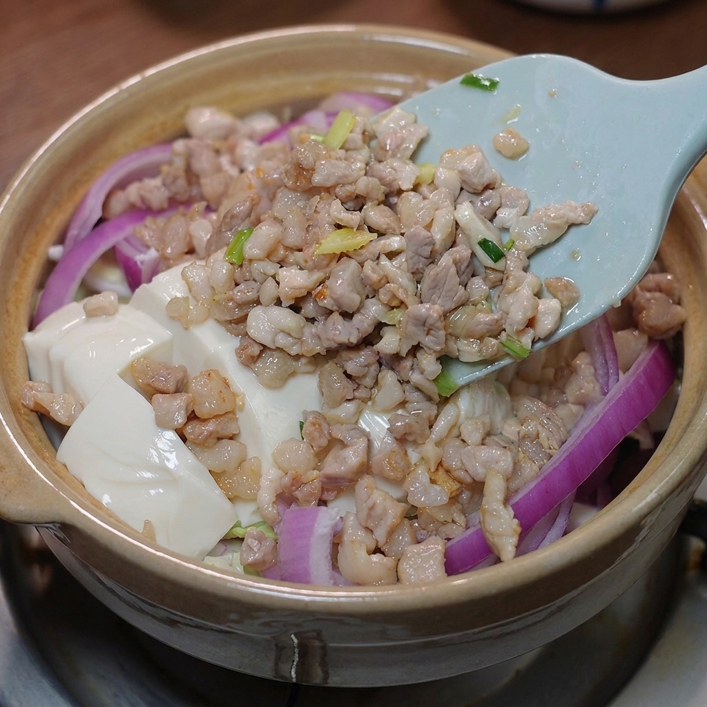 Angebratenes Fleisch und die Sauce werden über den Tofu gegeben.