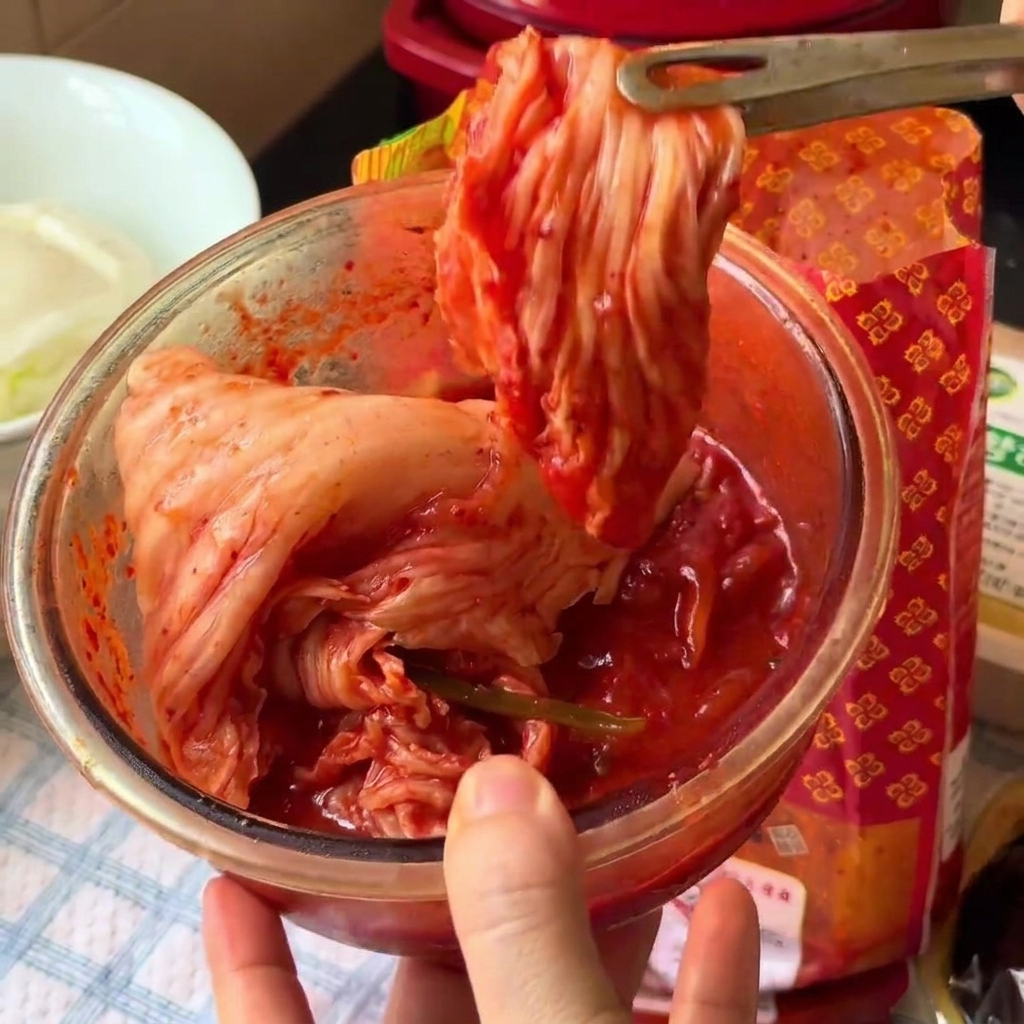 Kimchi wird in einer Glasschüssel mit einer Küchenschere in kleinere Stücke geschnitten.