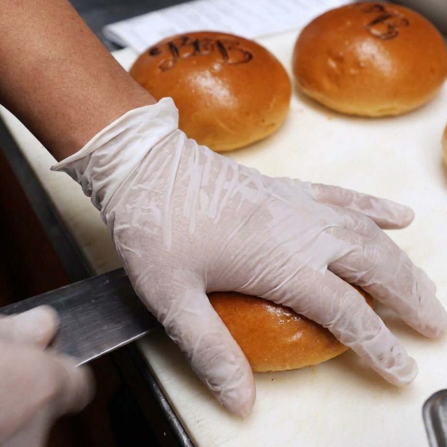 Burgerbrötchen werden aufgeschnitten und für den Grill mit Butter bestrichen.