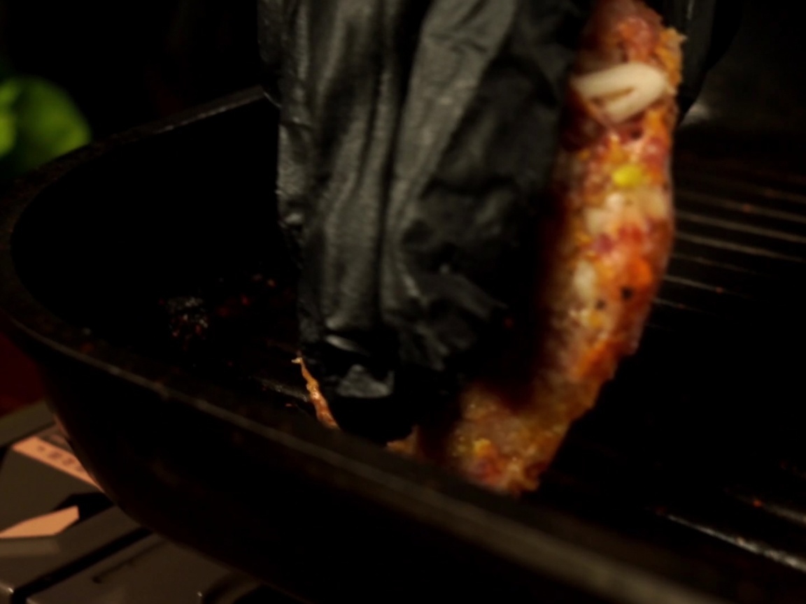 Ein rohes Rindfleisch-Patty wird in eine vorgeheizte Grillpfanne gelegt.