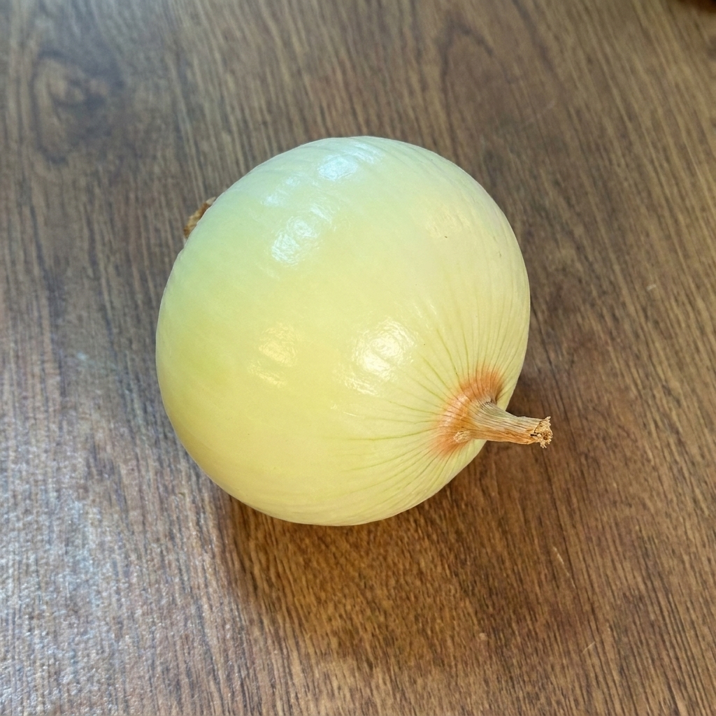 Eine geschälte, ganze Zwiebel auf einer Holzoberfläche.
