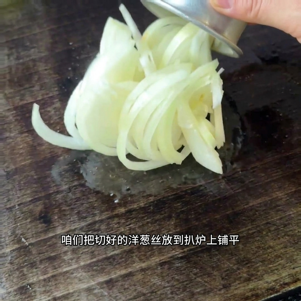 Frisch geschnittene Zwiebeln werden auf einer heißen Grillfläche verteilt.