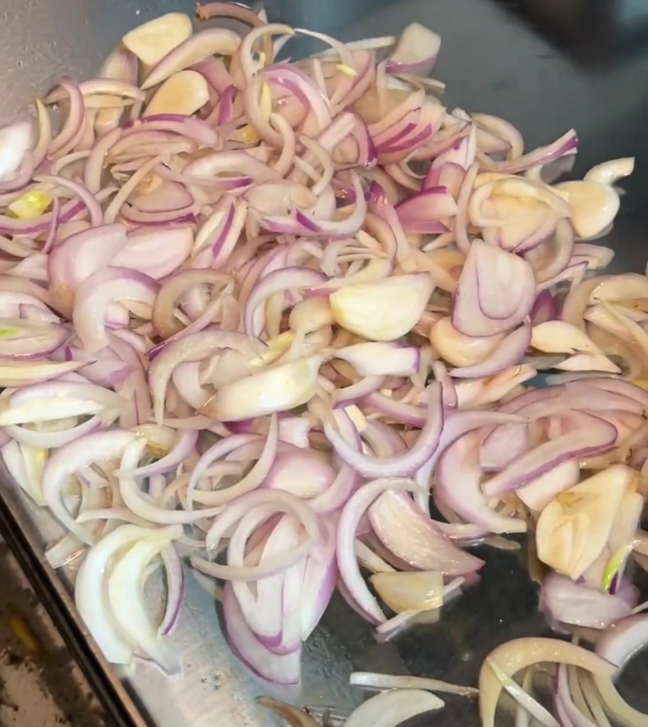 Geschnittene Zwiebeln werden mit einem Metallspatel in einer heißen Pfanne gewendet.