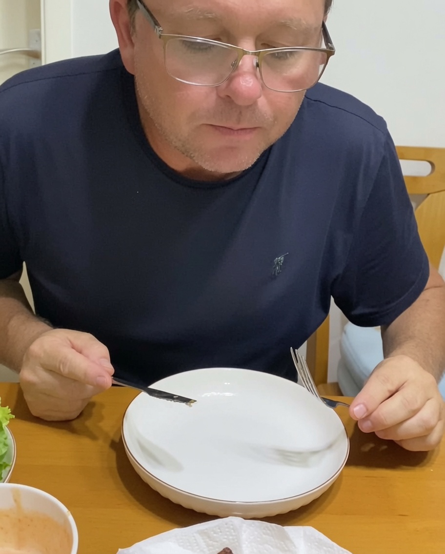 Ein Burger wird auf einem Teller angerichtet, mit karamellisierten Zwiebeln und frischem Gemüse auf dem Patty.